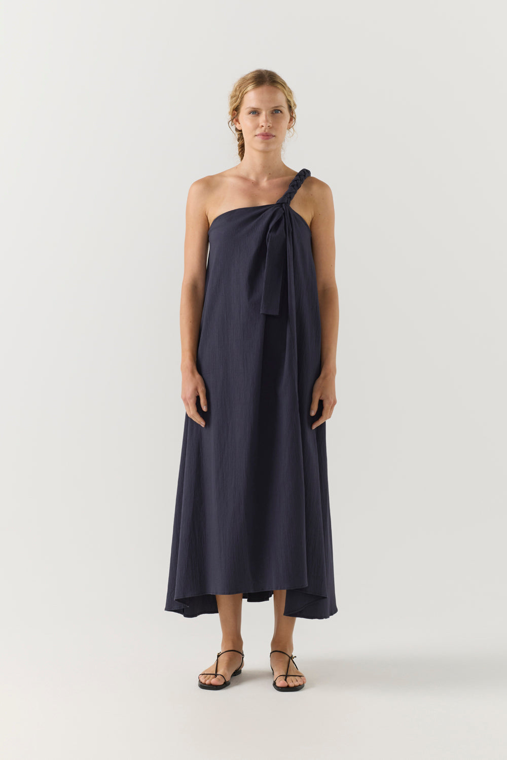 Woman wearing a navy one-shoulder dress on a white background