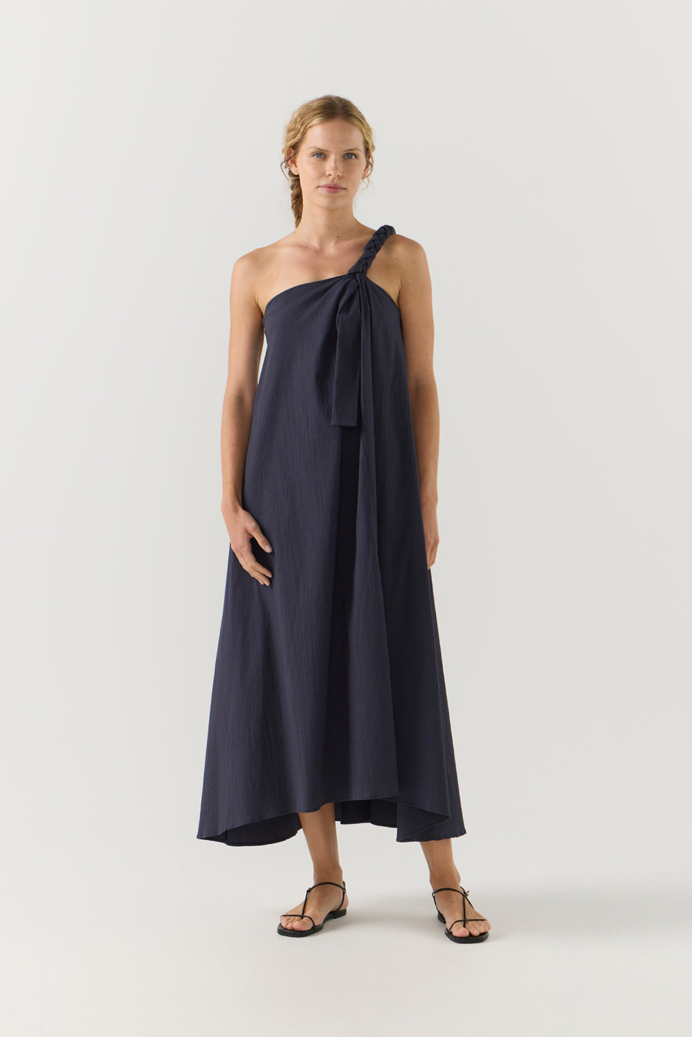 Woman wearing a navy one-shoulder dress on a white background