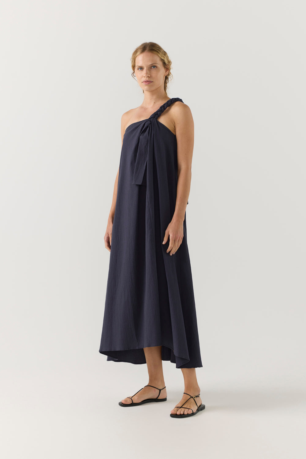 Woman wearing a navy one-shoulder dress on a white background