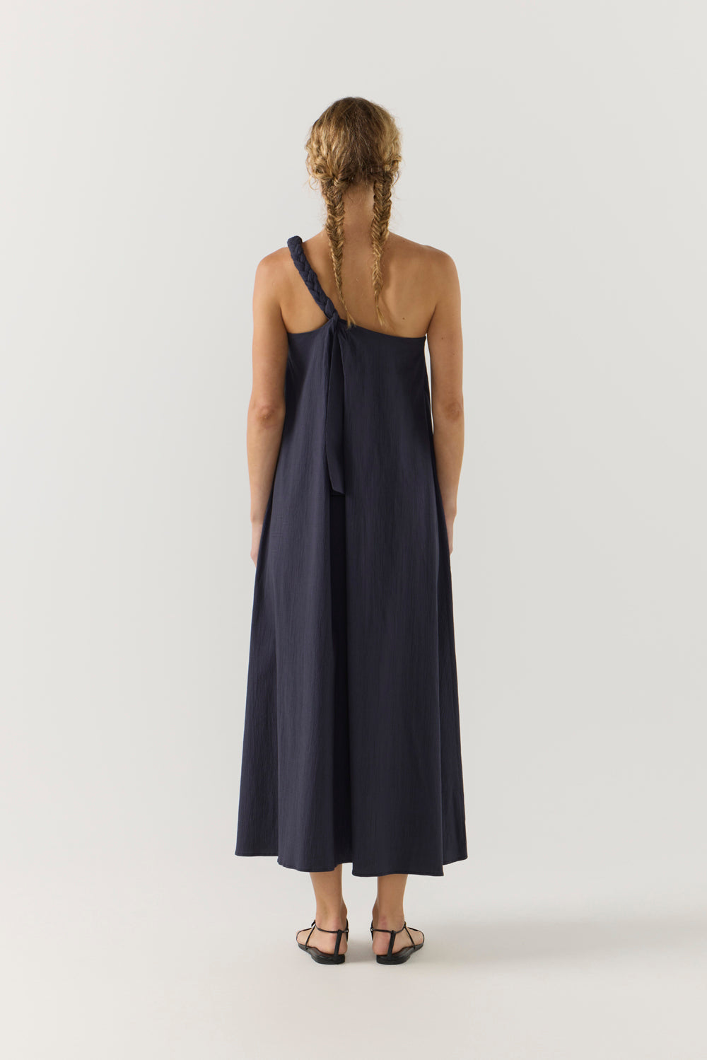 Woman wearing a navy one-shoulder dress on a white background