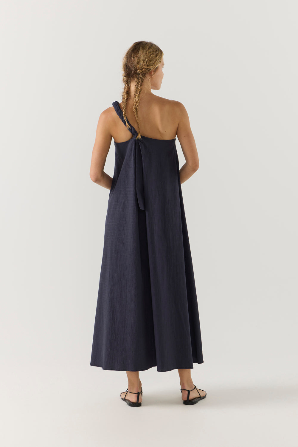 Woman wearing a navy one-shoulder dress on a white background