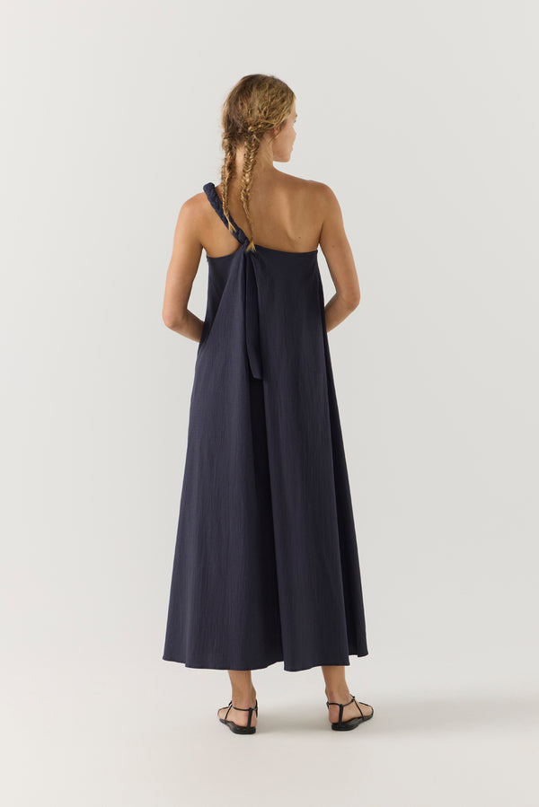 Woman wearing a navy one-shoulder dress on a white background