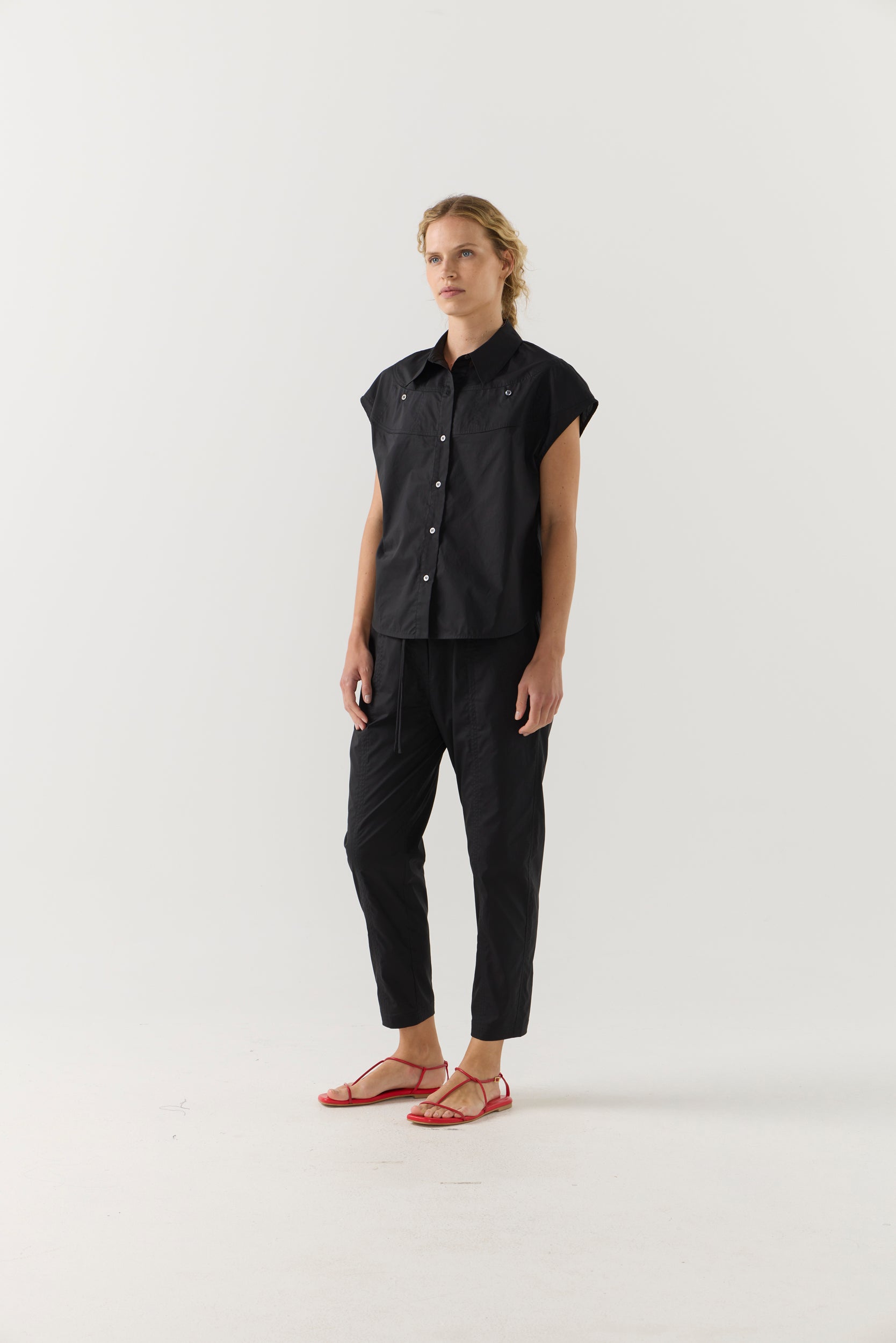 Person wearing a black sleeveless shirt and pants on a white background