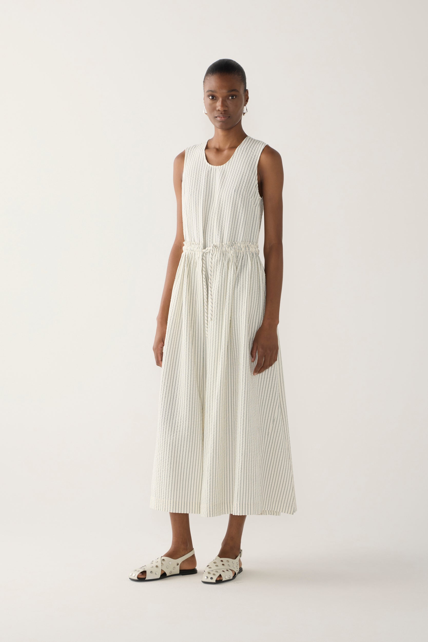 Woman wearing a white sleeveless dress on a plain background