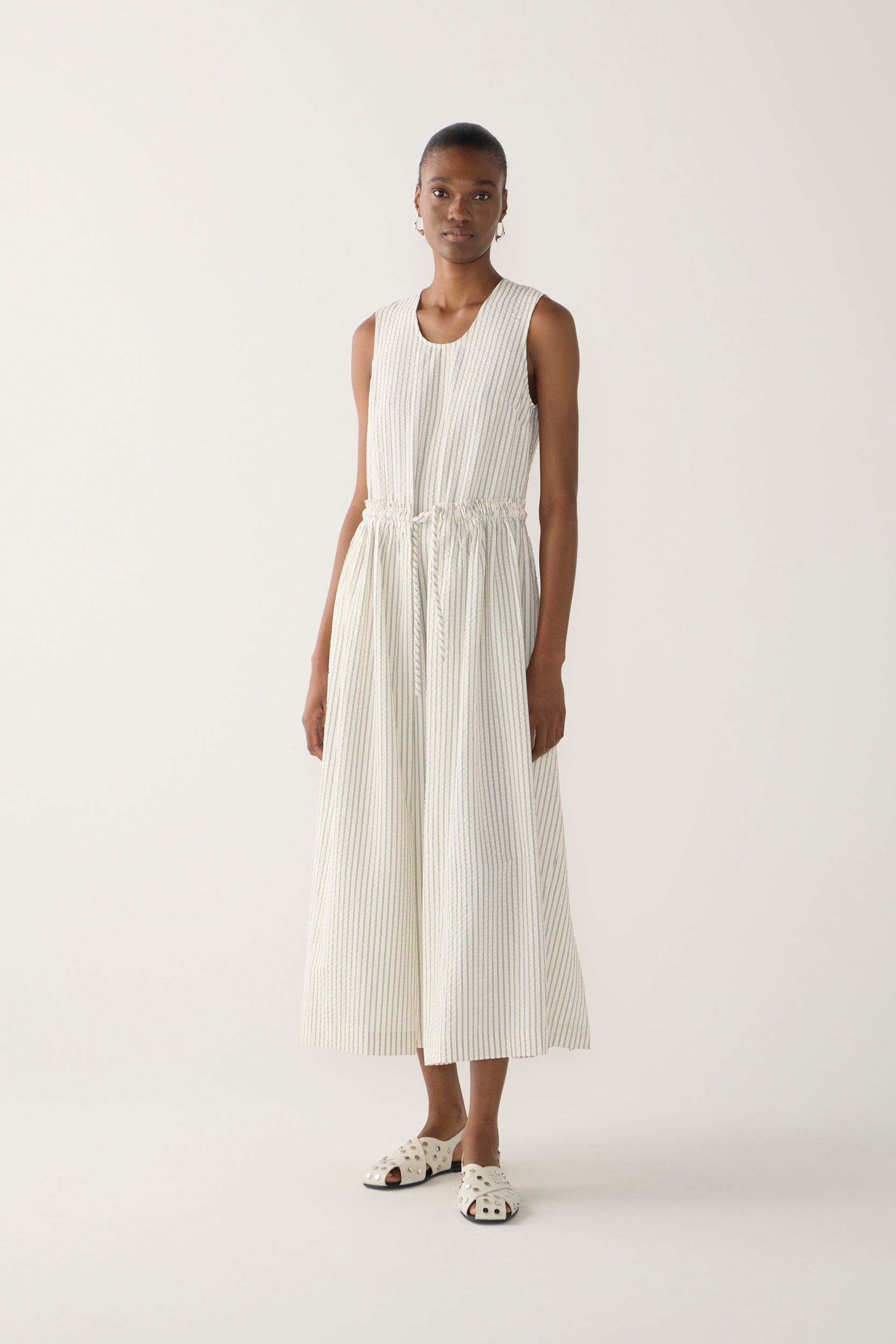 Woman wearing a white sleeveless dress on a plain background