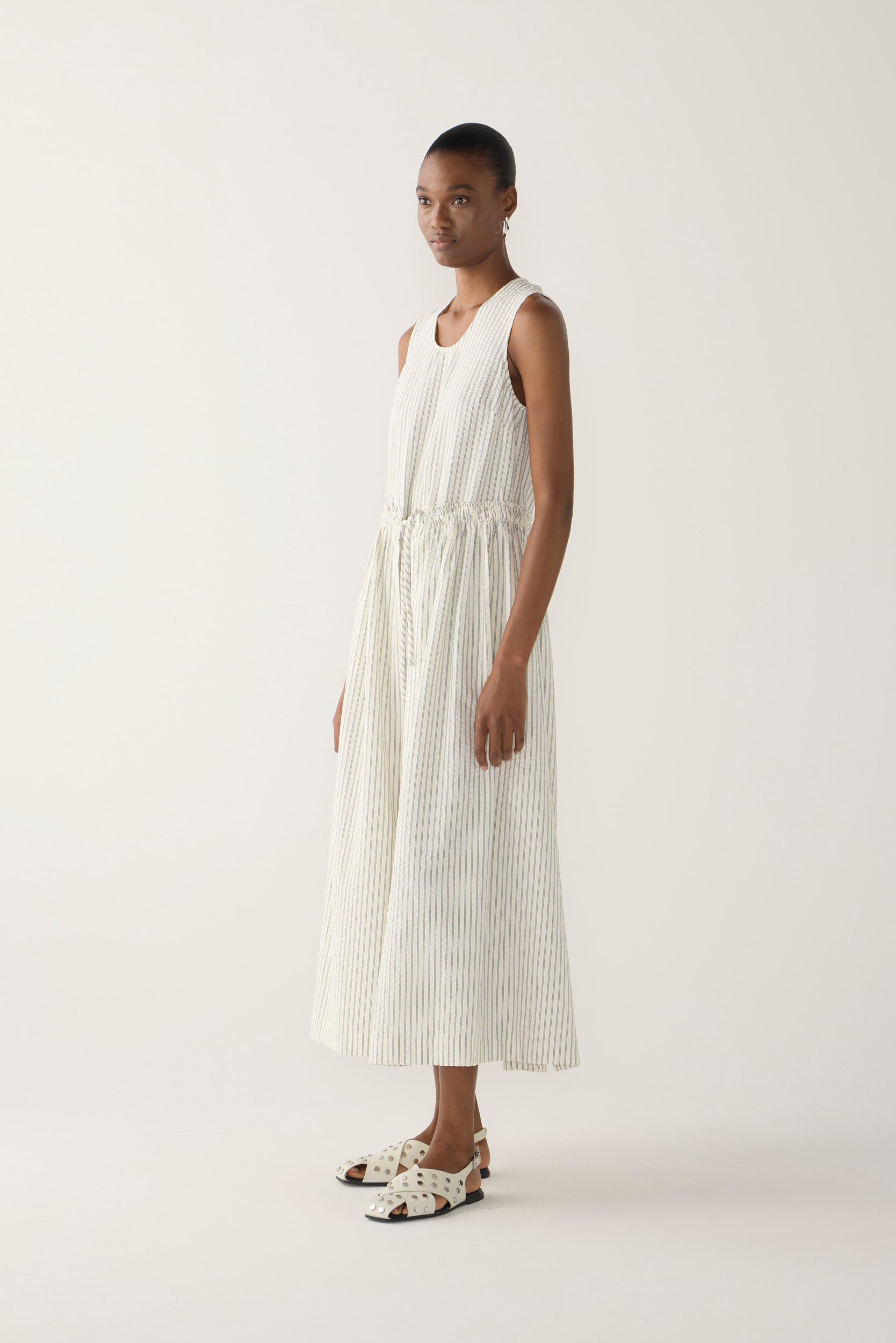 Woman wearing a white sleeveless dress on a plain background