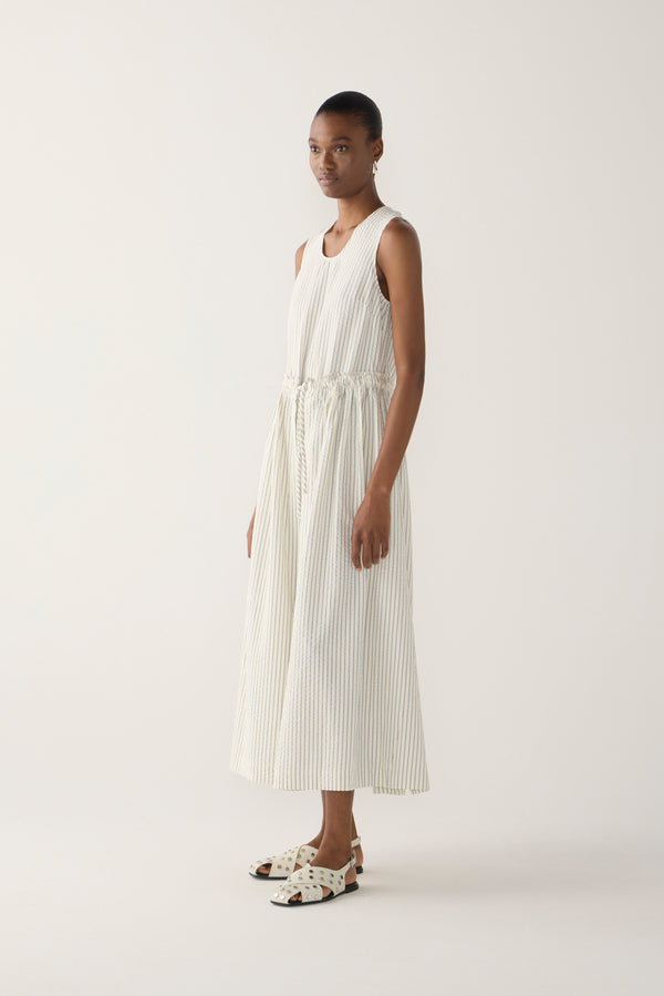 Woman wearing a white sleeveless dress on a plain background