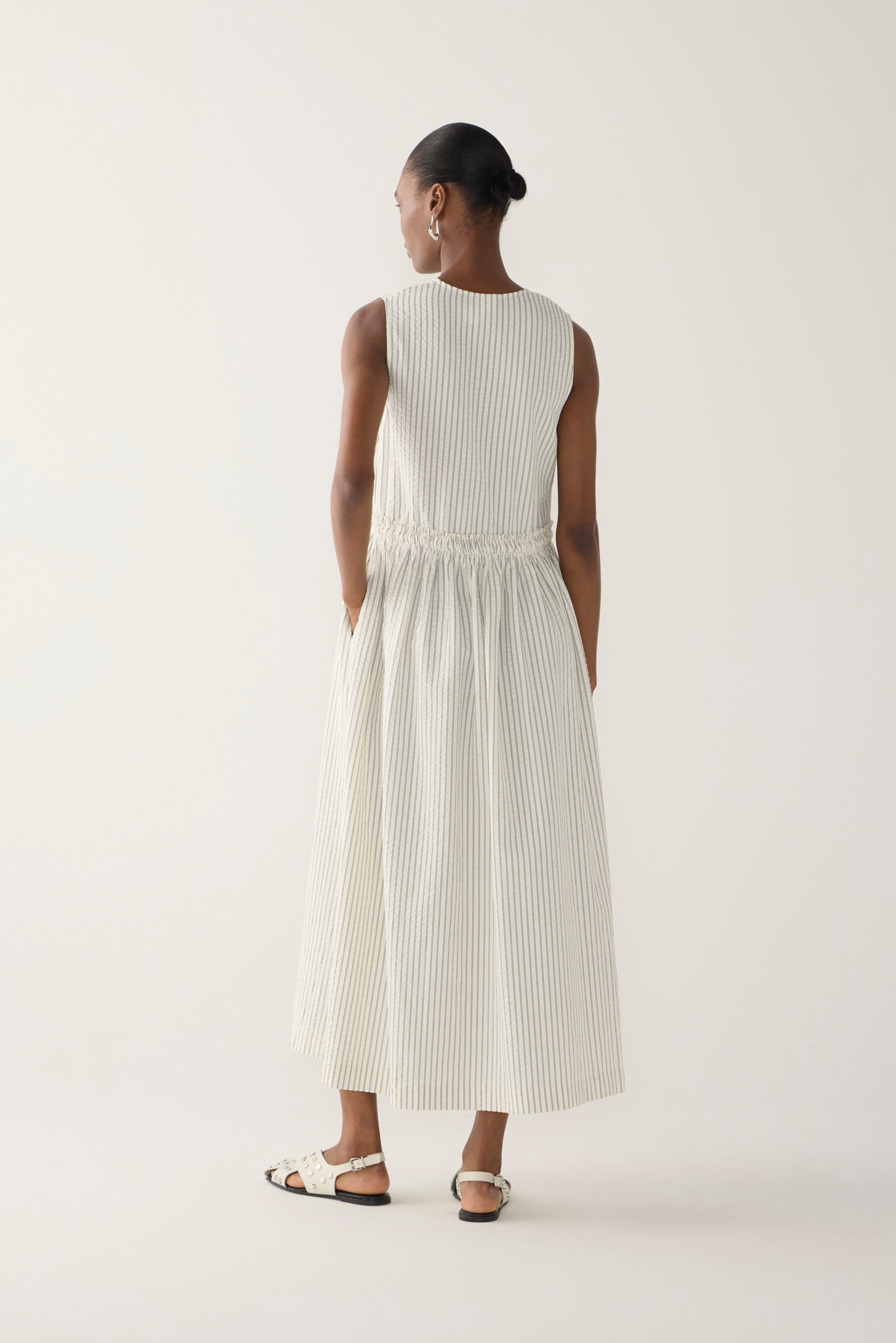 Woman wearing a white sleeveless dress on a plain background