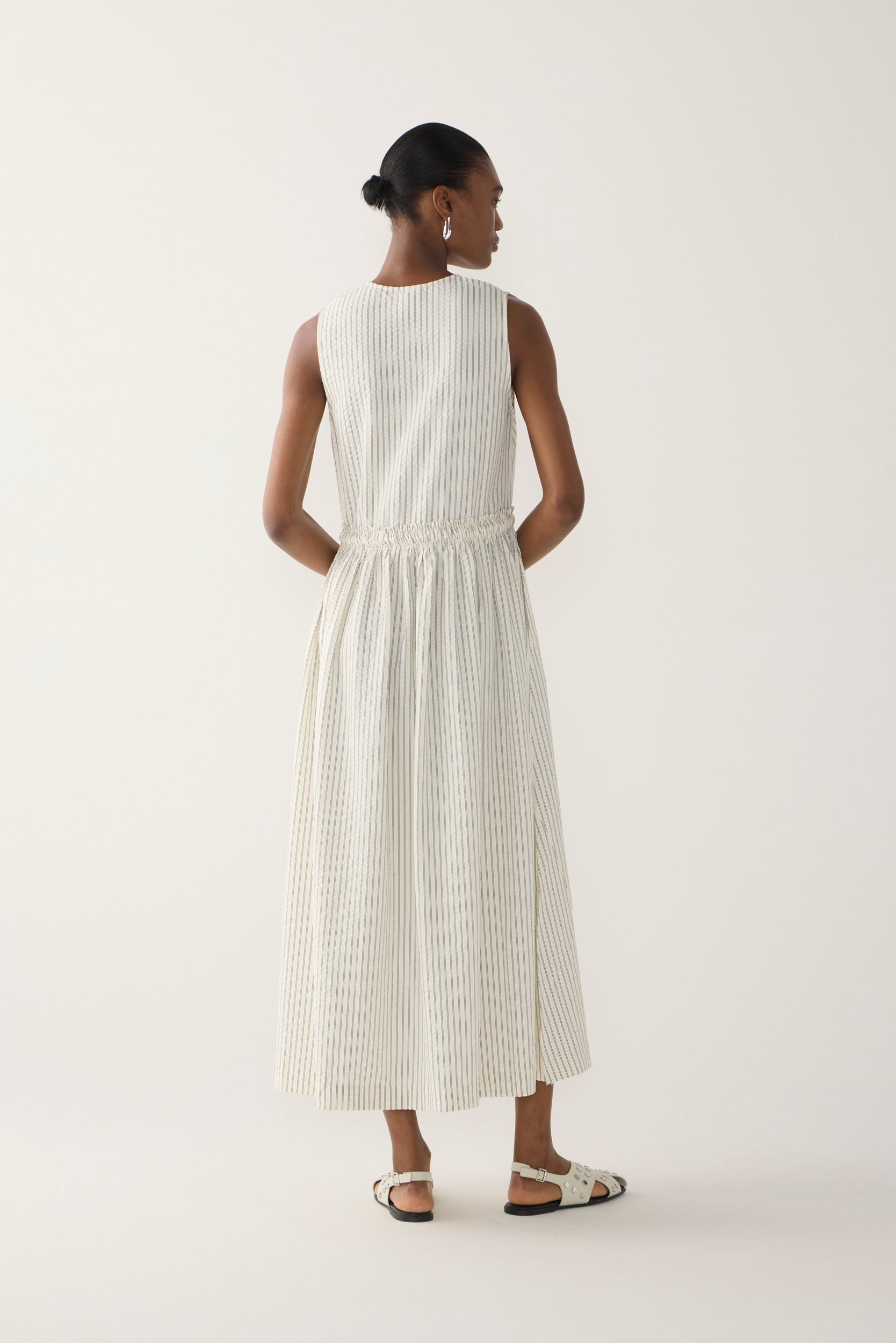Woman wearing a white sleeveless dress on a plain background