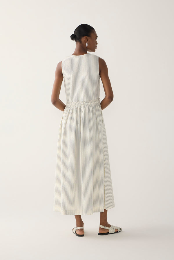 Woman wearing a white sleeveless dress on a plain background