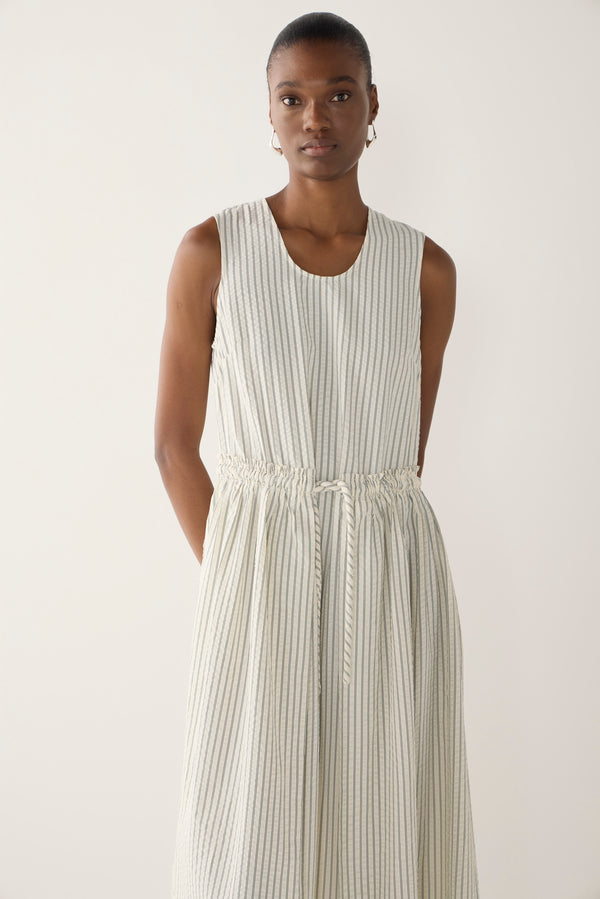 Woman wearing a white sleeveless dress on a plain background