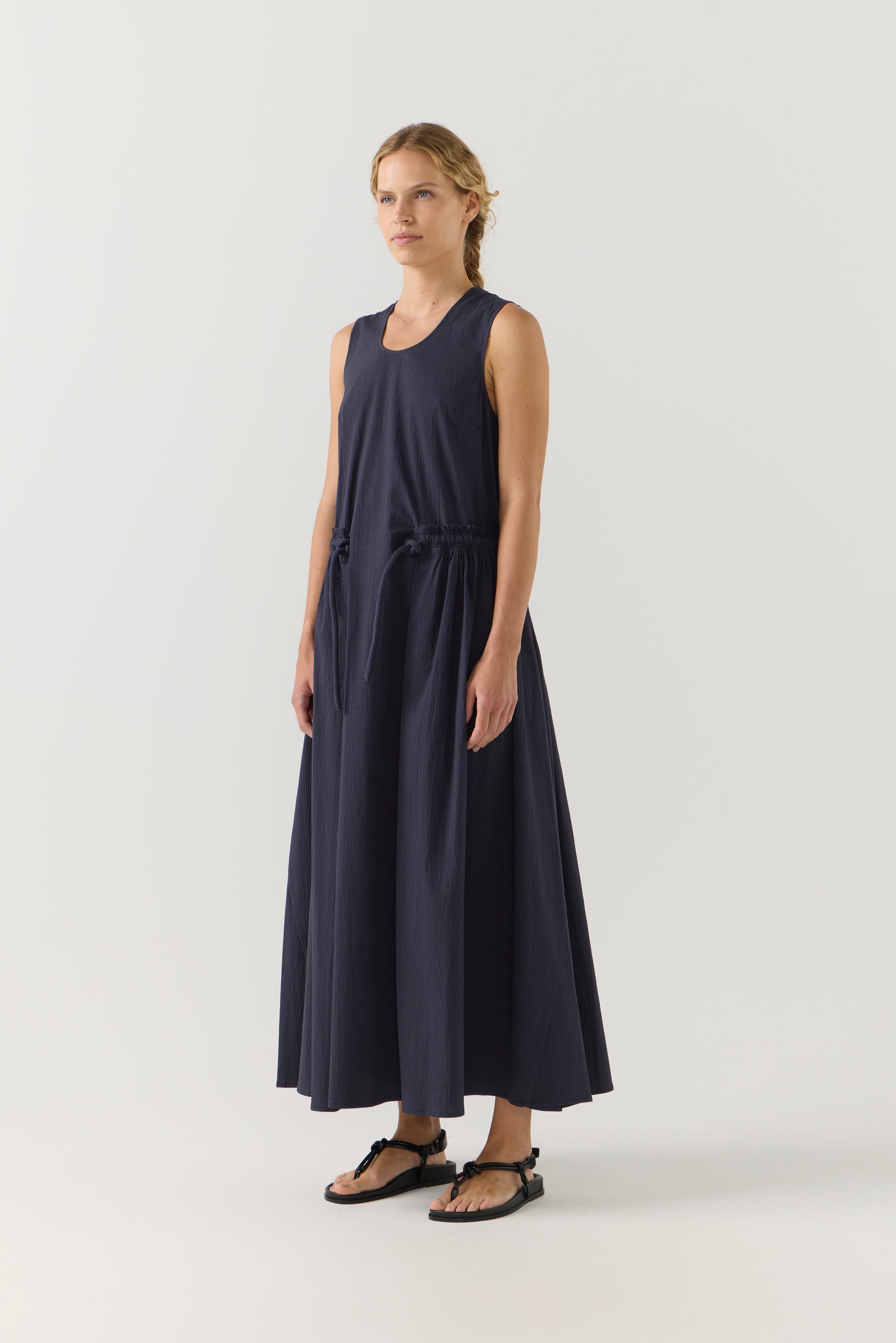 Woman wearing a navy sleeveless dress on a white background