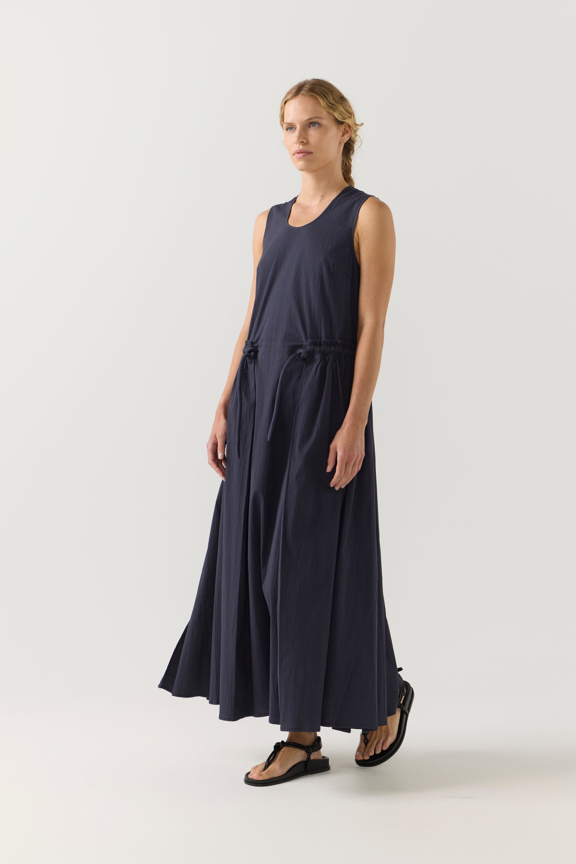 Woman wearing a long navy dress on a white background