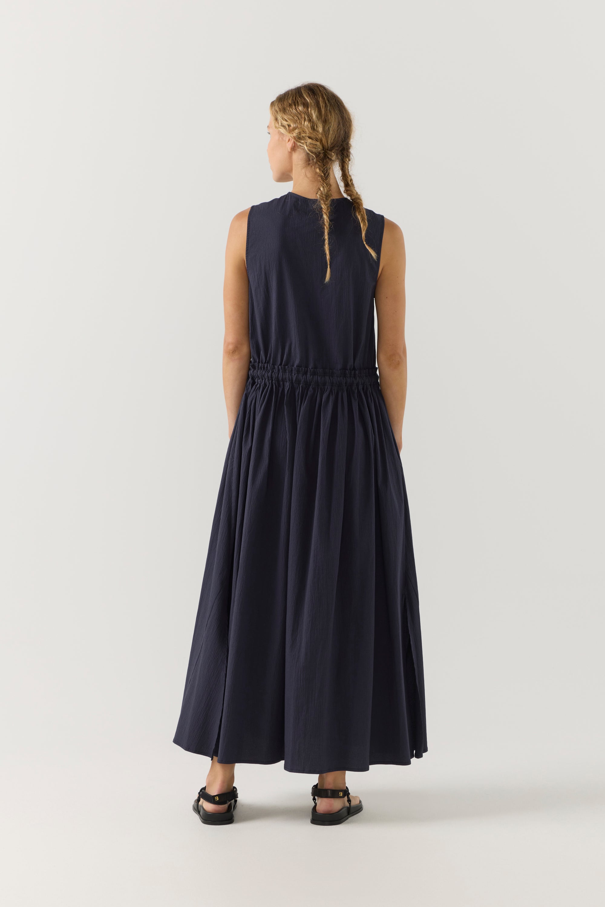 Woman wearing a navy sleeveless dress on a white background