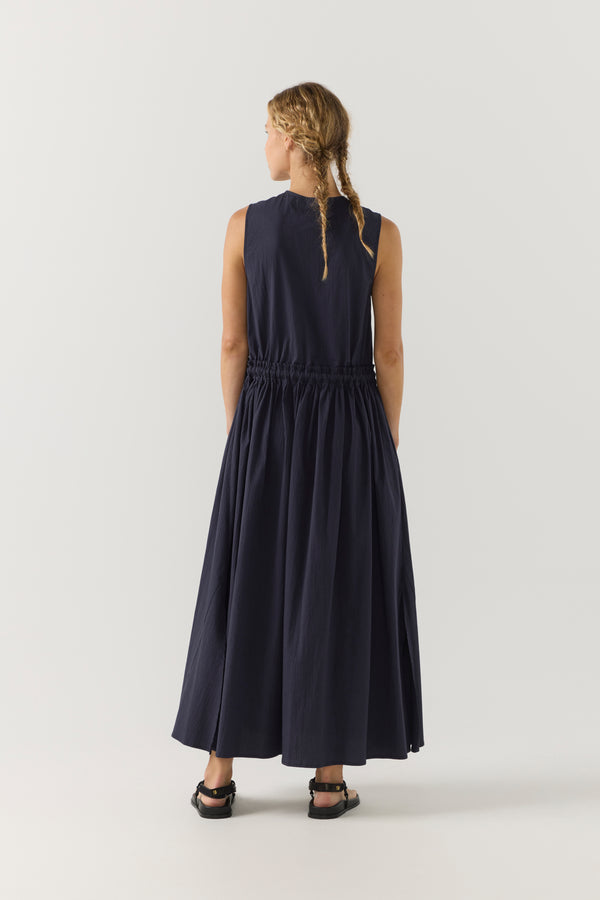 Woman wearing a navy sleeveless dress on a white background