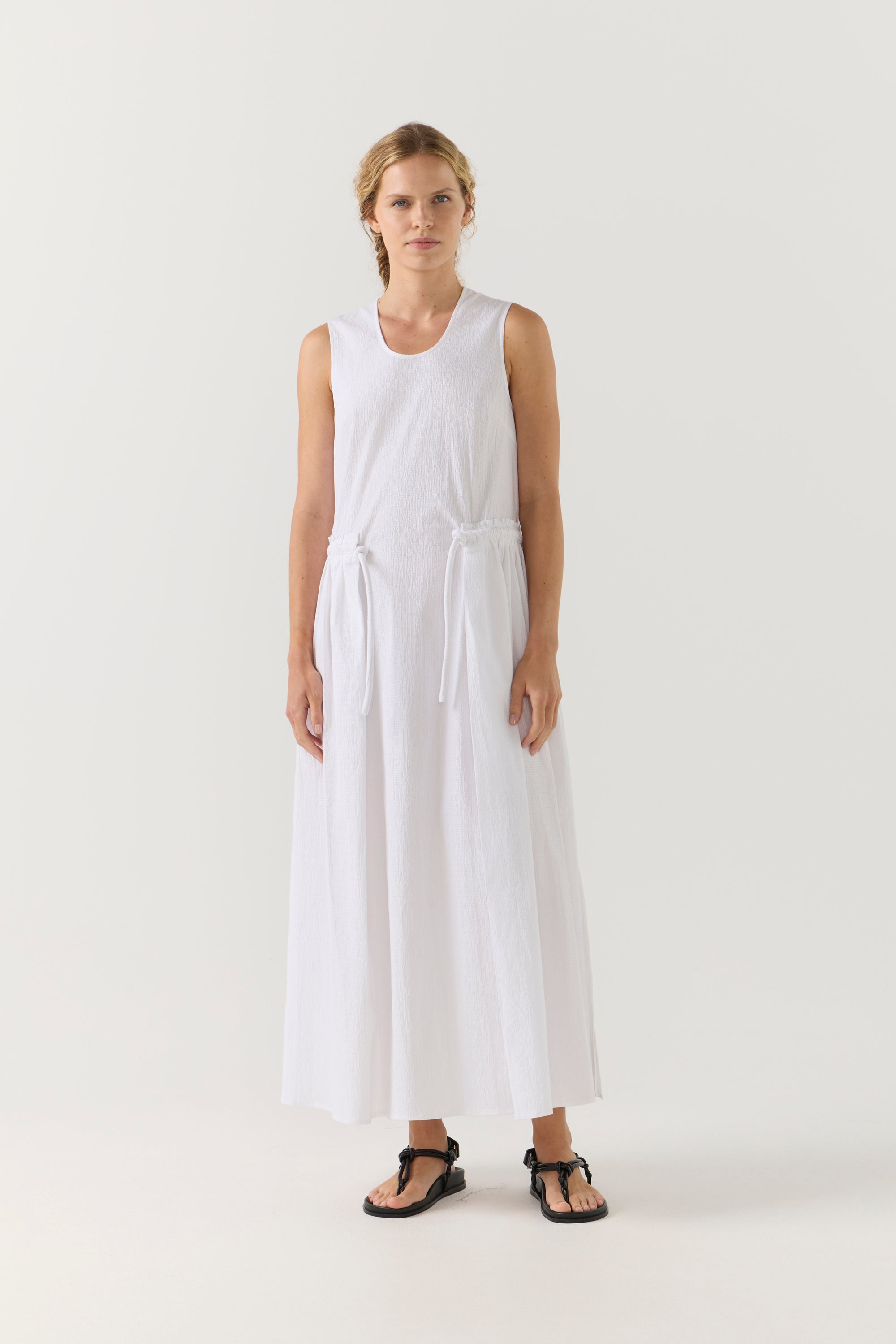 Woman wearing a white sleeveless dress on a plain background