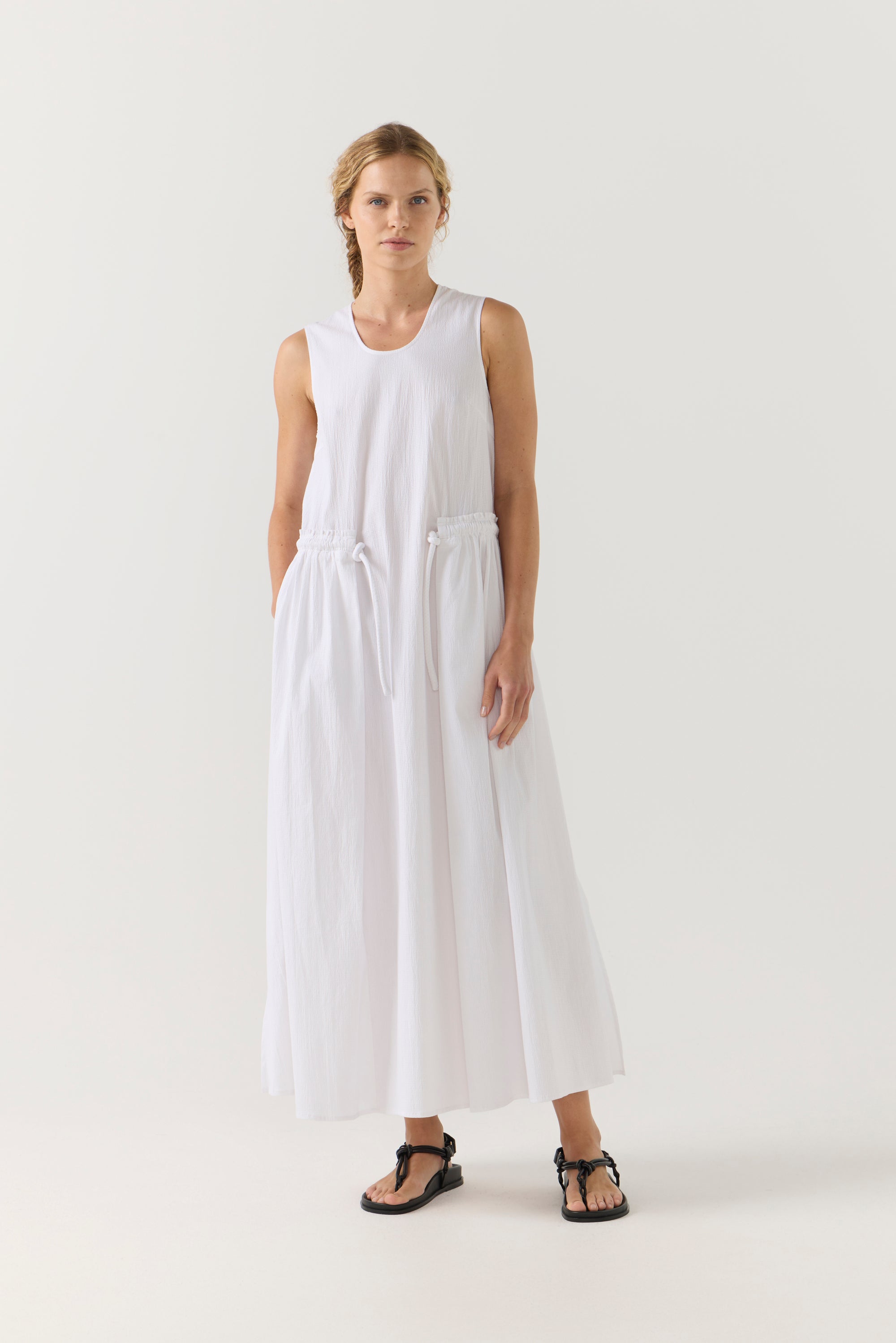 Woman wearing a white sleeveless jumpsuit on a plain background