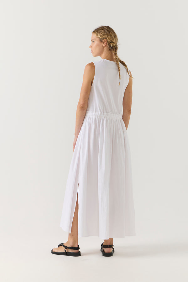 Woman wearing a white sleeveless dress on a plain background