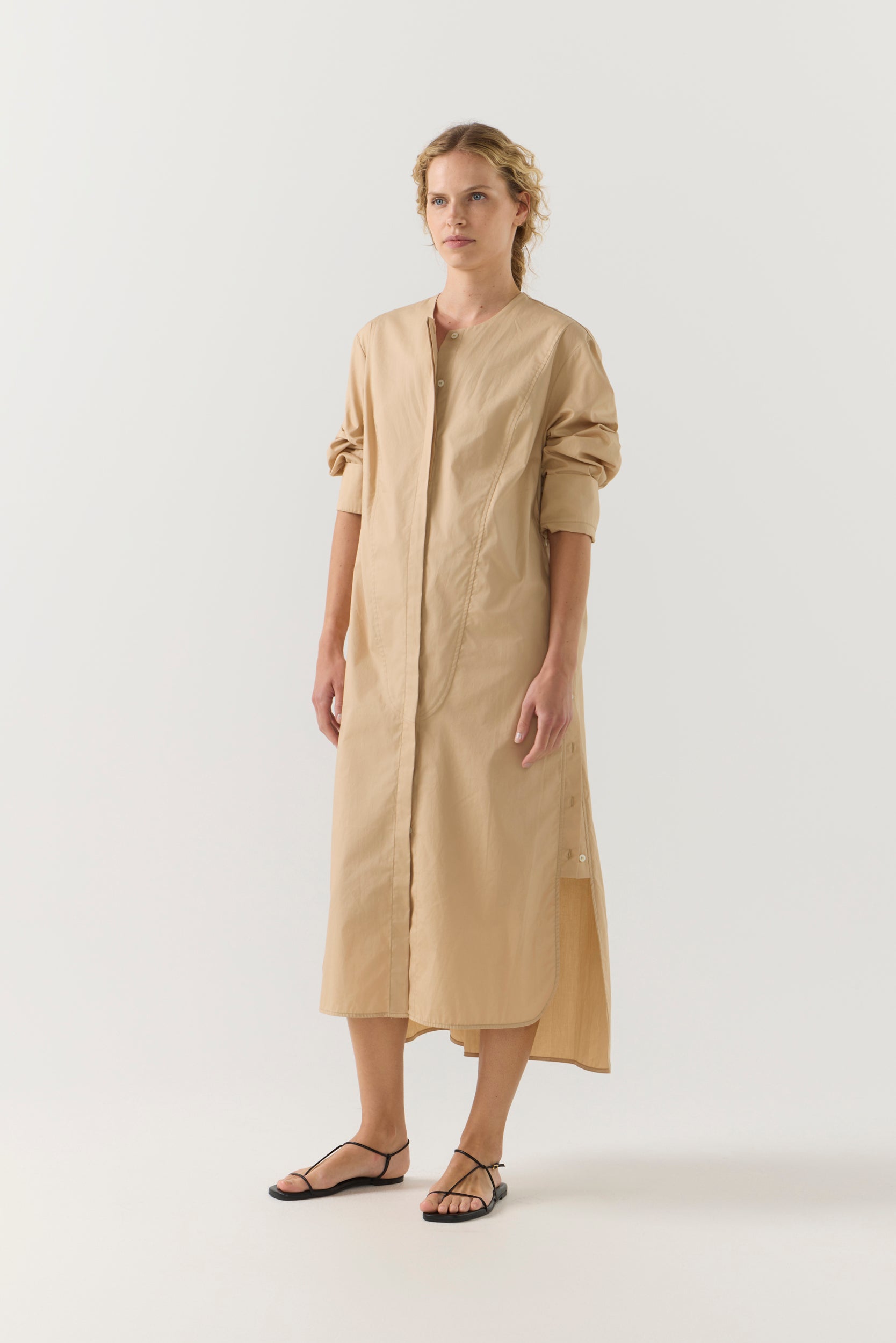Woman wearing a beige dress with a belt on a white background