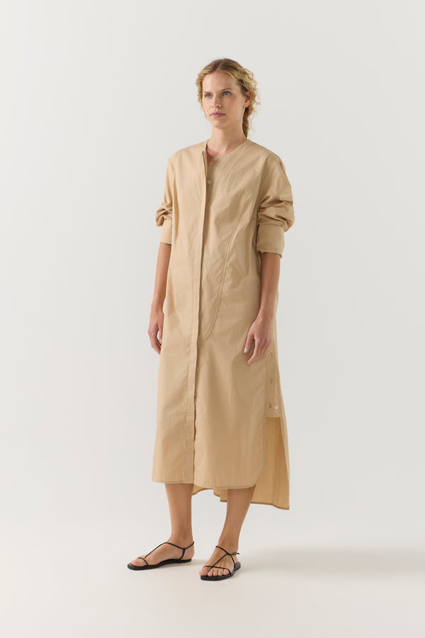 Woman wearing a beige dress with a belt on a white background