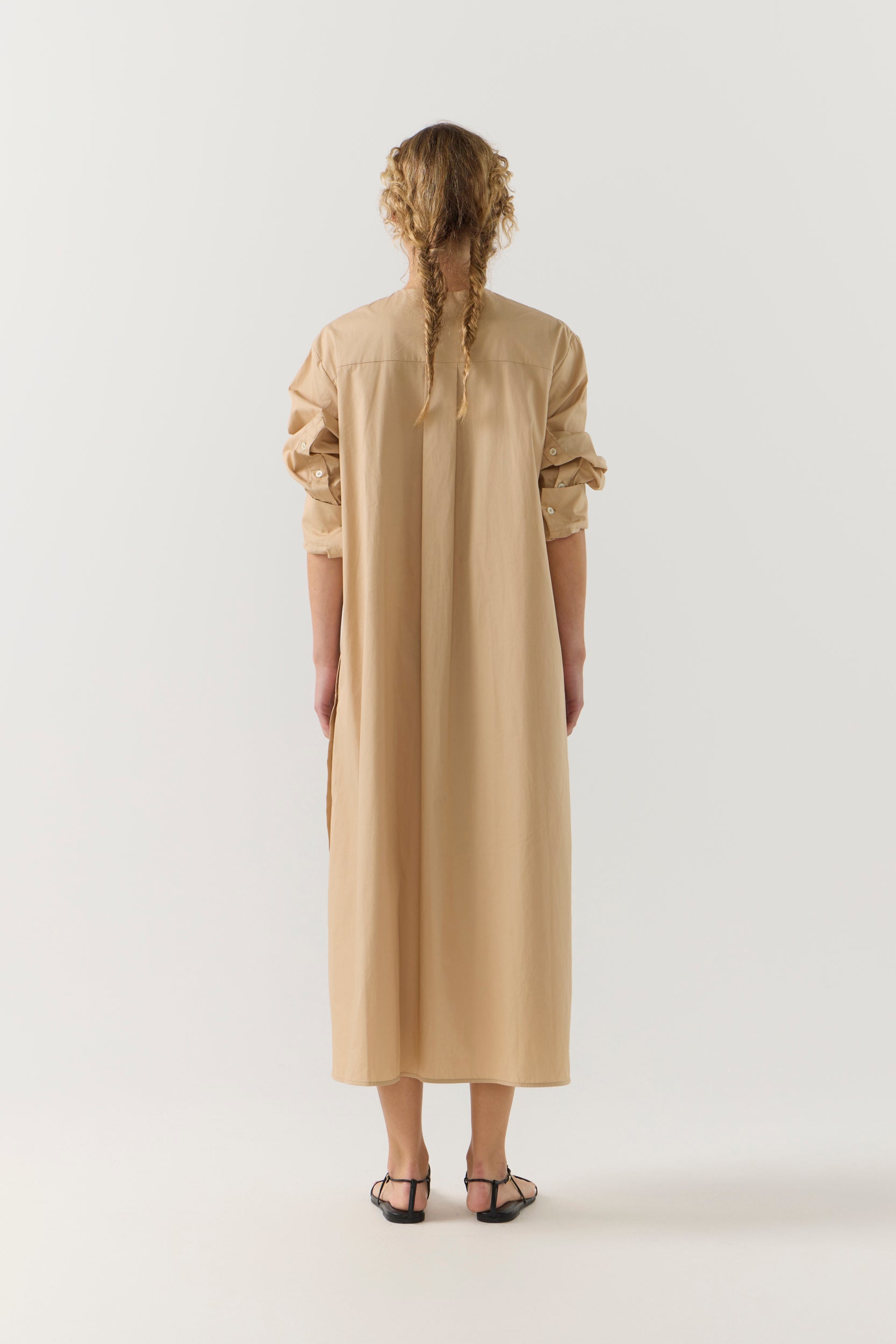 Woman wearing a beige dress with a belt on a white background