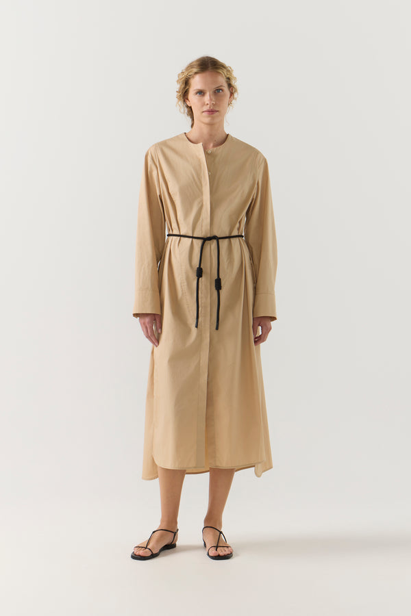 Woman wearing a beige dress with a belt on a white background