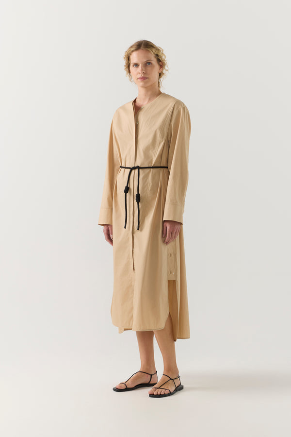 Woman wearing a beige dress with a belt on a white background