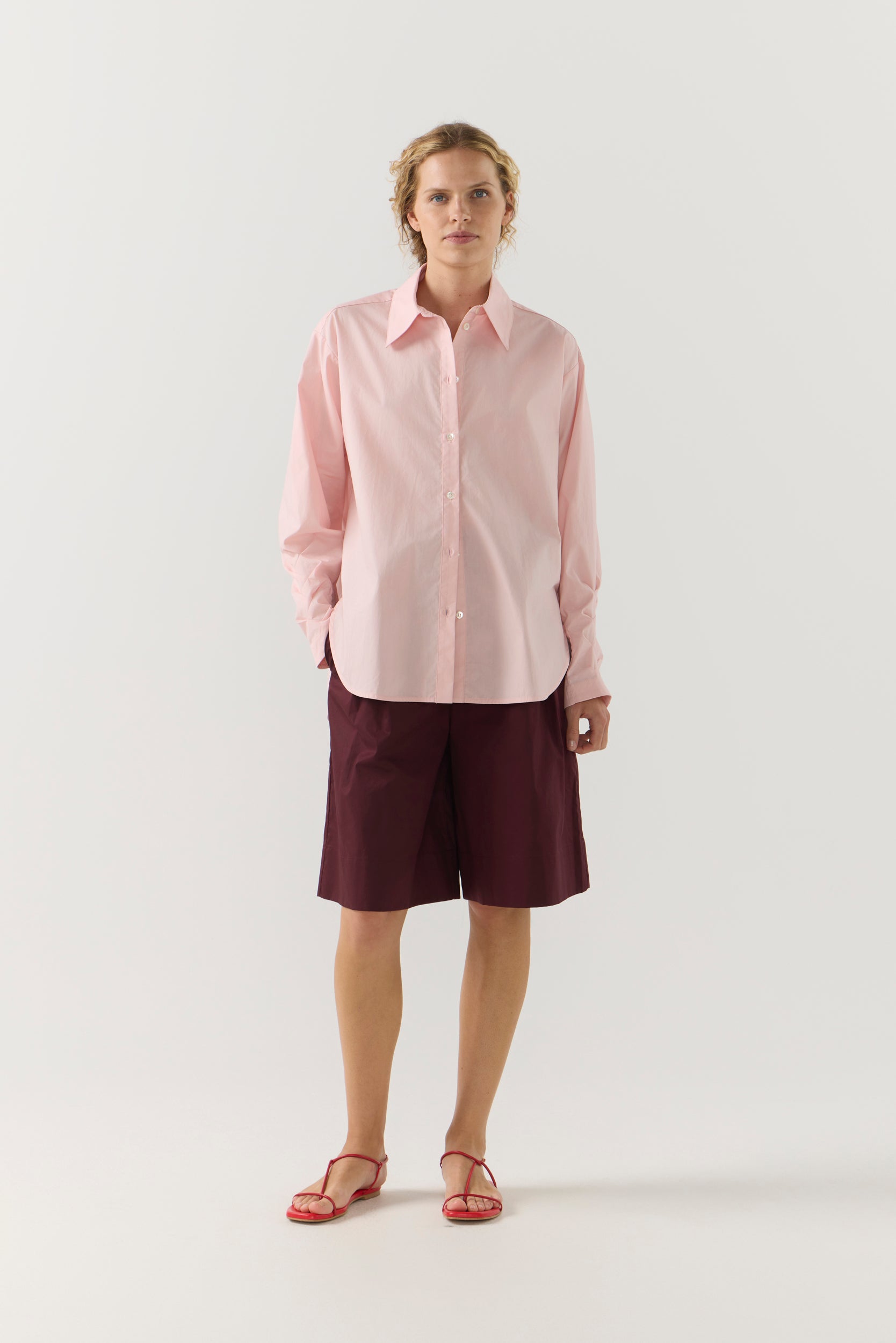 Woman wearing a light pink shirt against a plain background