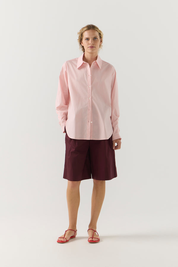 Woman wearing a light pink shirt against a plain background