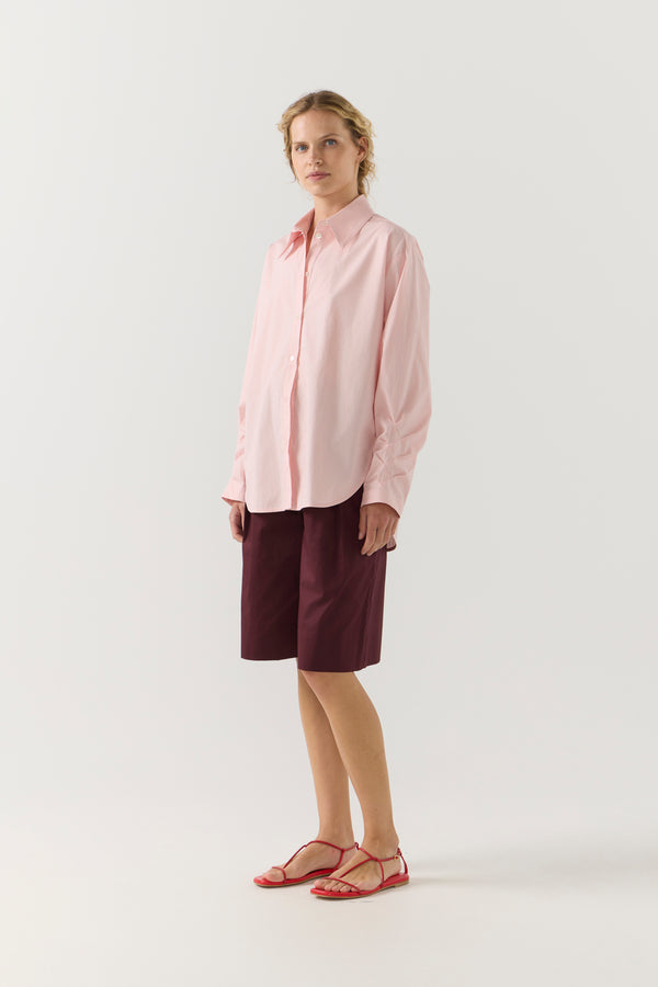 Woman wearing a light pink shirt against a plain background