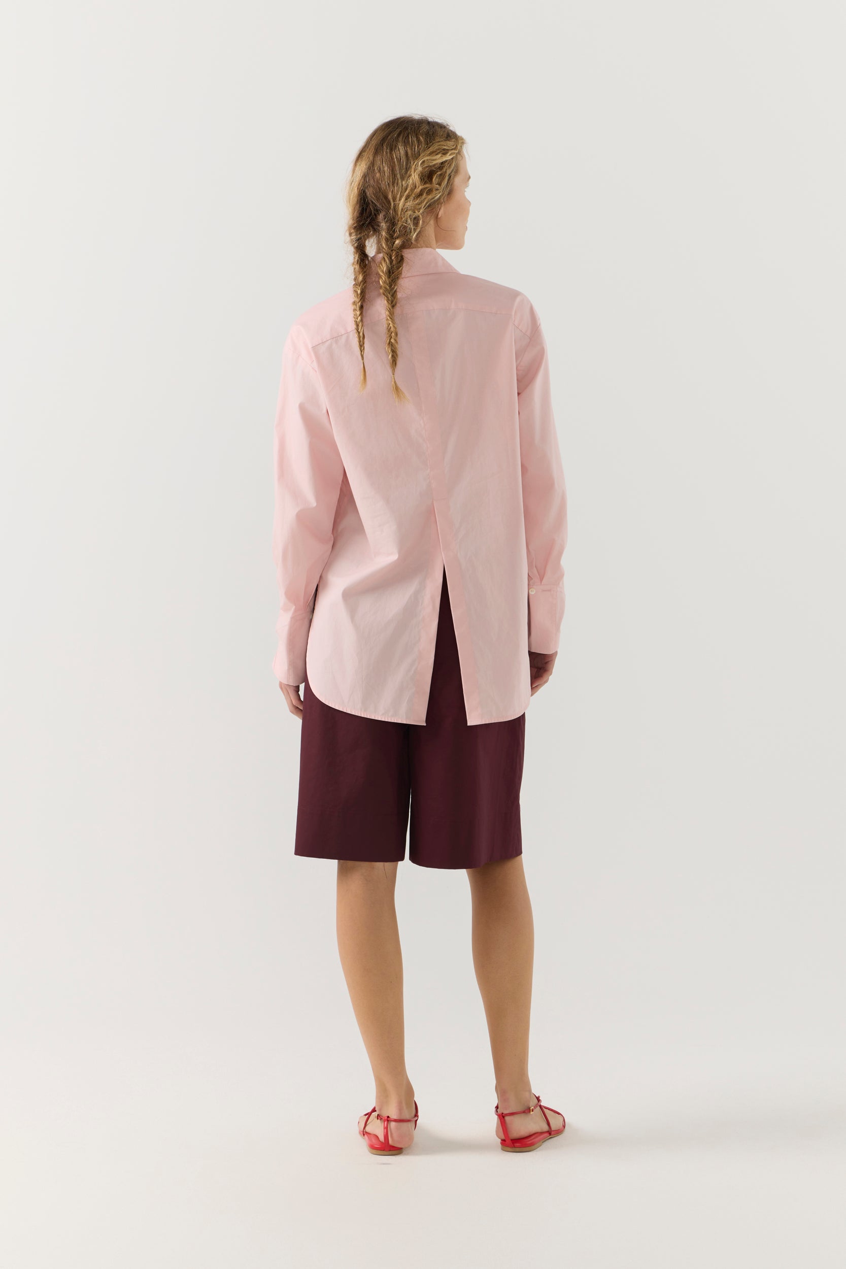 Woman wearing a light pink shirt against a plain background