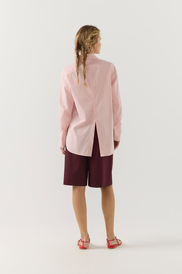 Woman wearing a light pink shirt against a plain background