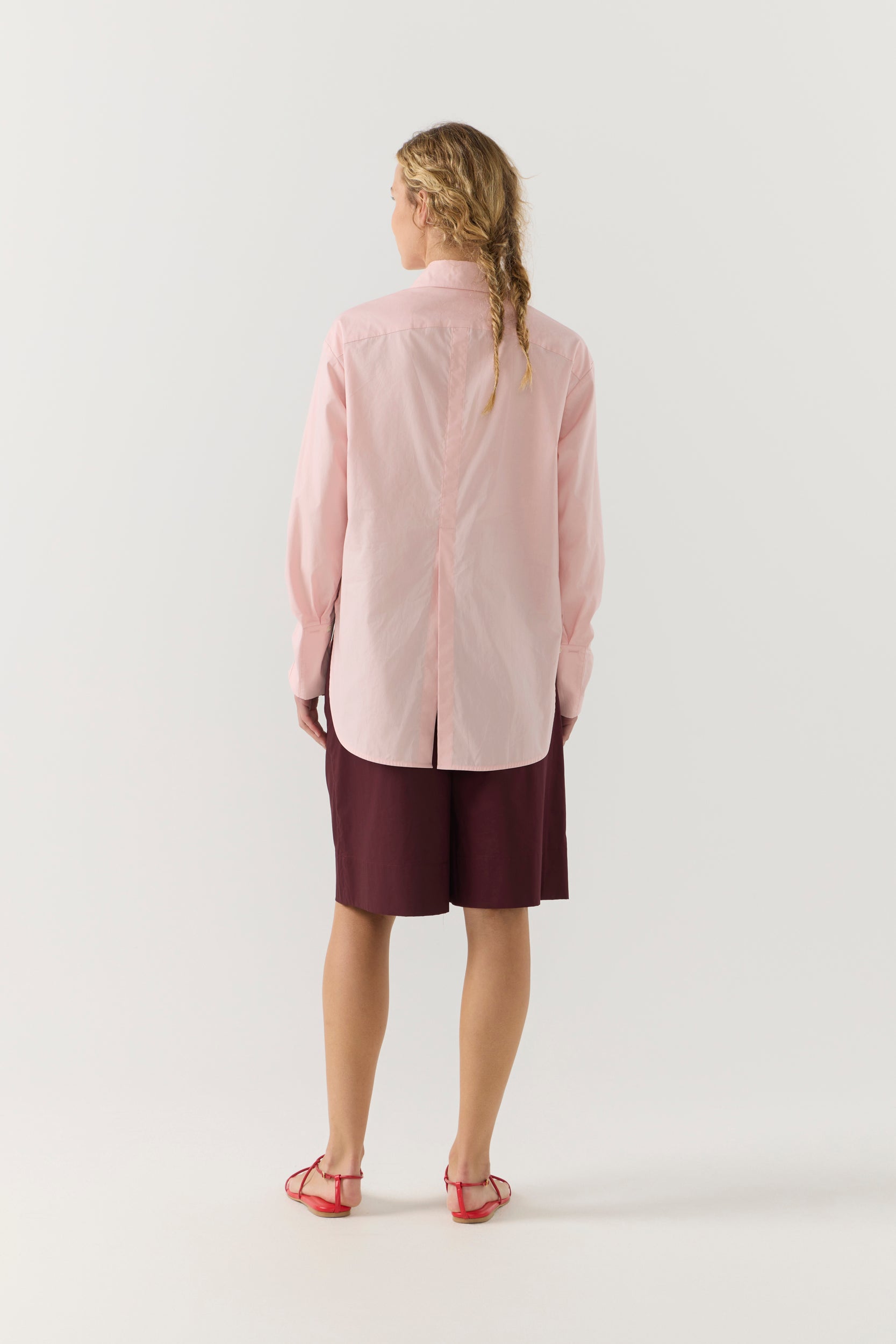 Woman wearing a light pink shirt against a plain background