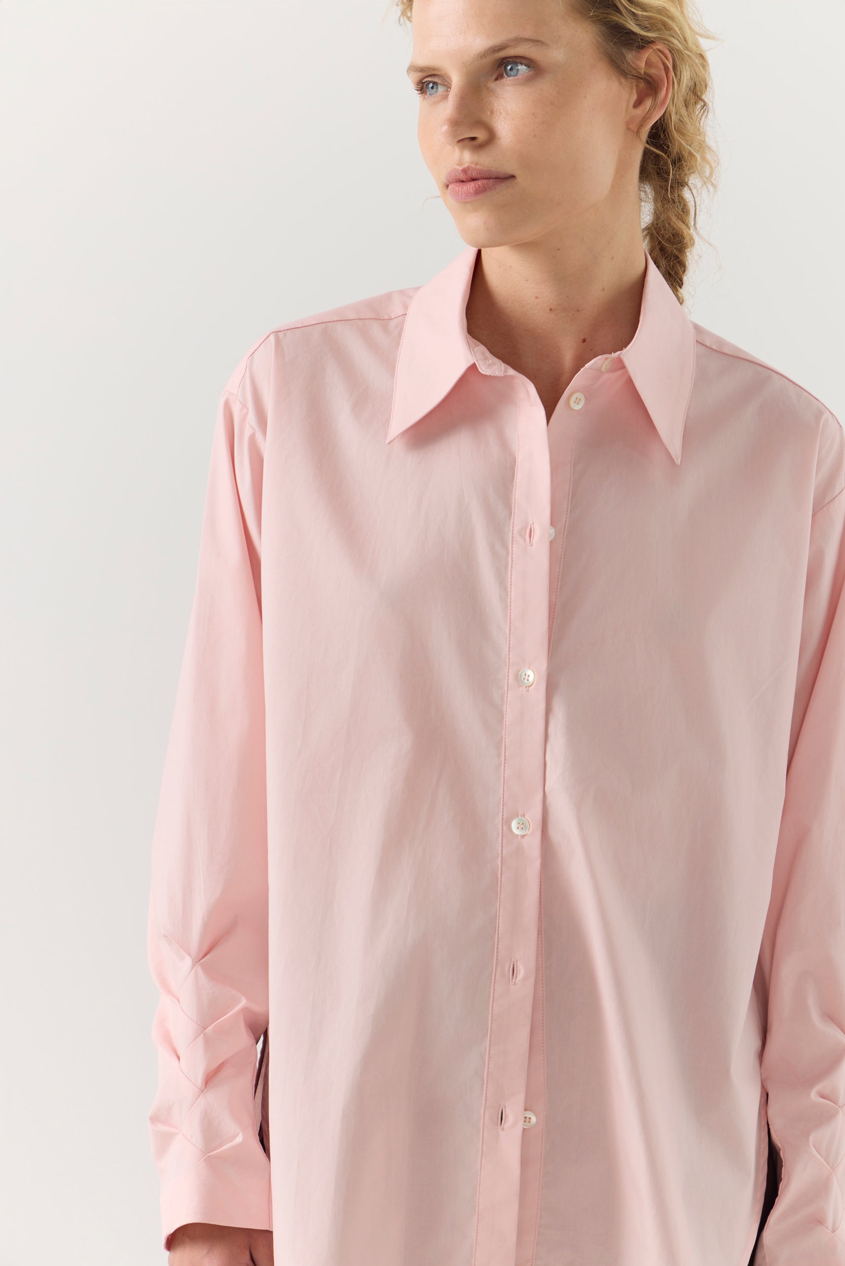 Woman wearing a light pink shirt against a plain background