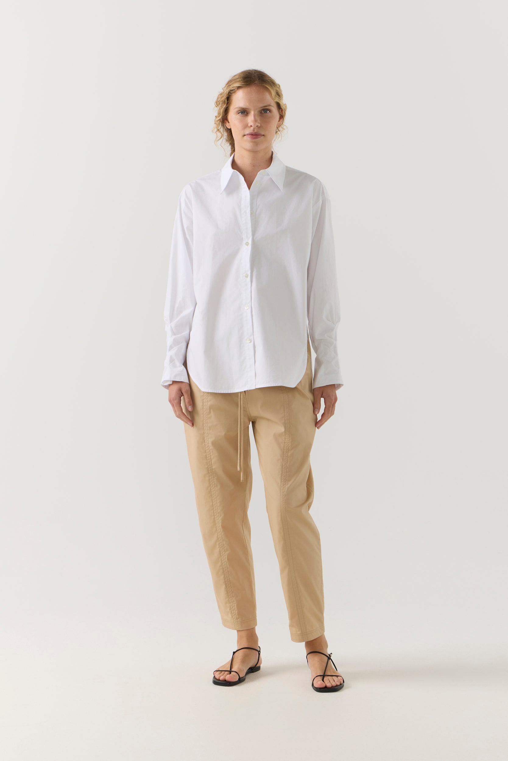 Person wearing a white shirt and beige pants on a white background
