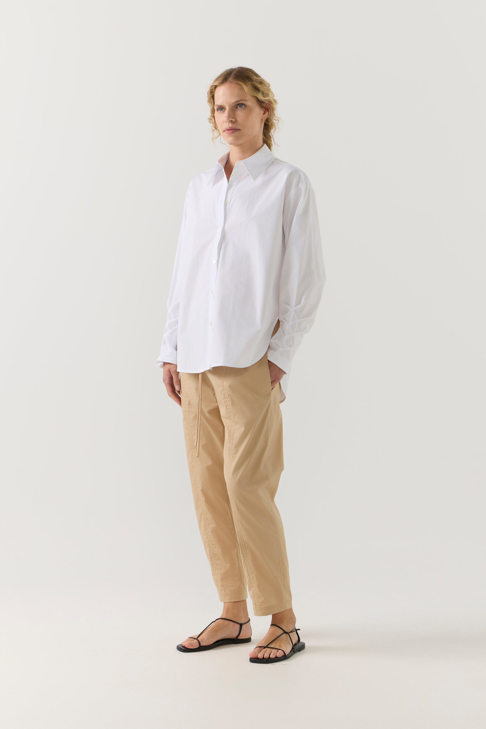 Person wearing a white shirt and beige pants on a white background