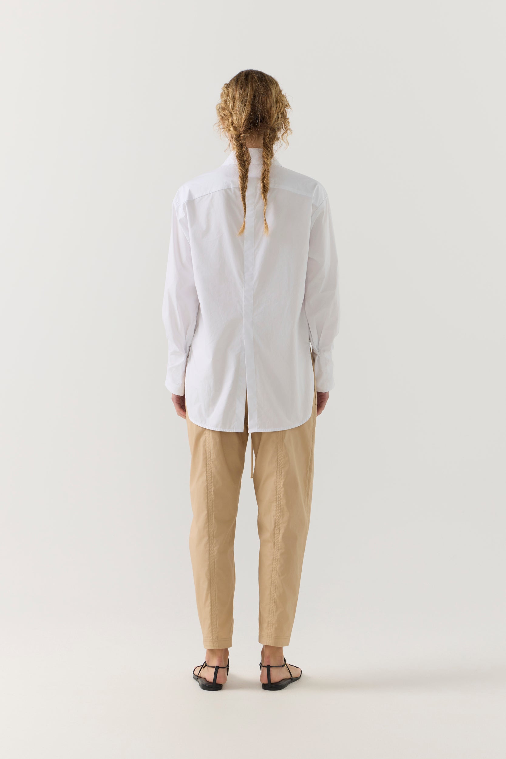 Person wearing a white shirt and beige pants on a white background