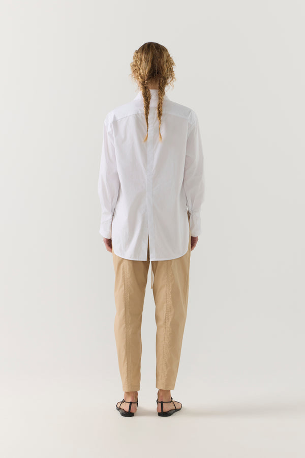 Person wearing a white shirt and beige pants on a white background