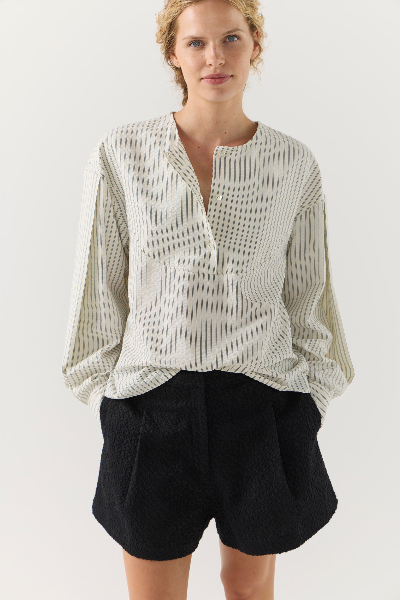 Woman wearing a striped shirt and black shorts on a white background