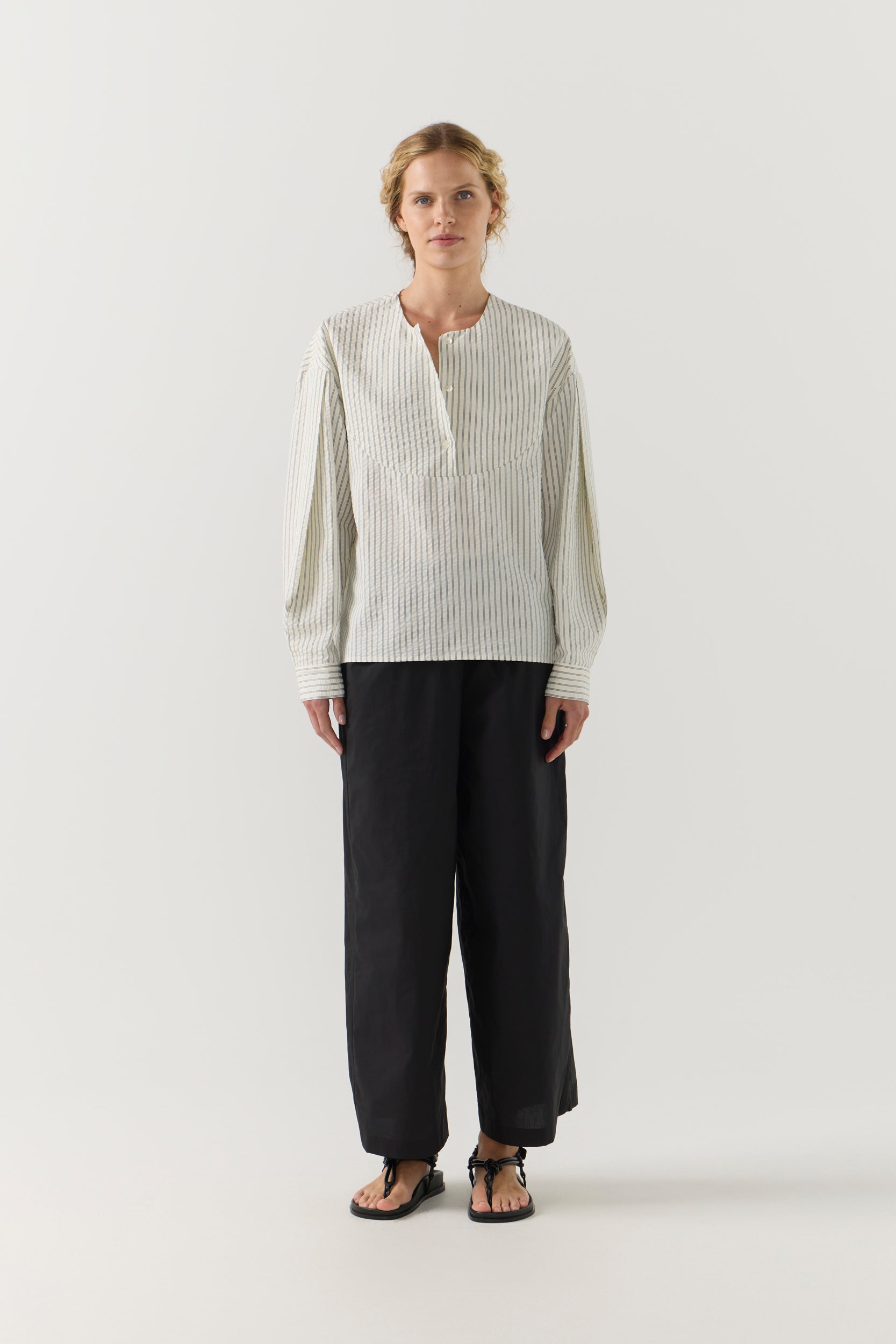 Woman wearing a striped shirt and black shorts on a white background