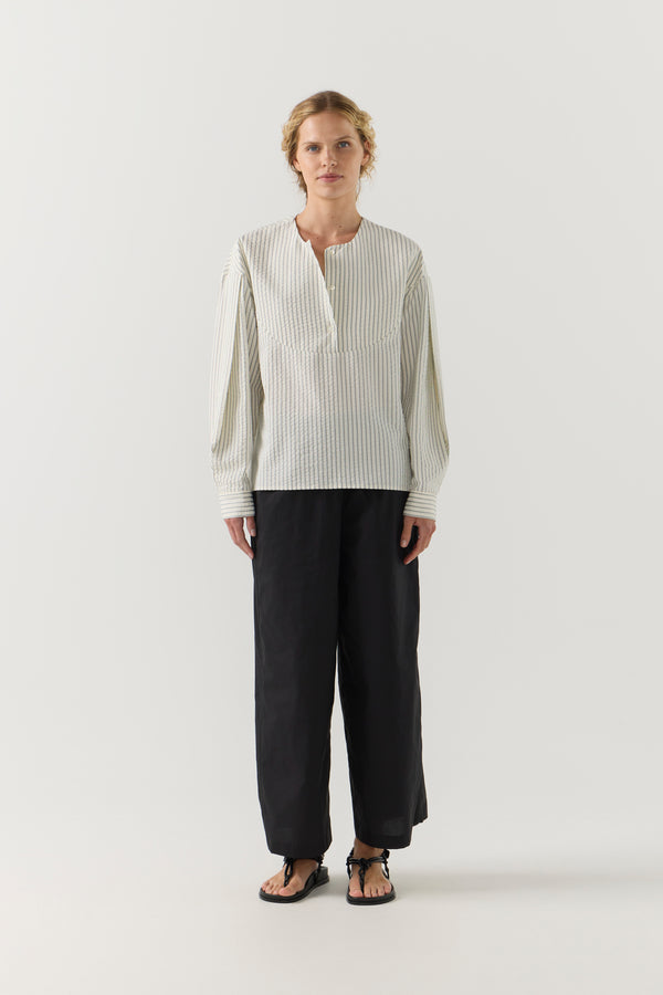 Woman wearing a striped shirt and black shorts on a white background