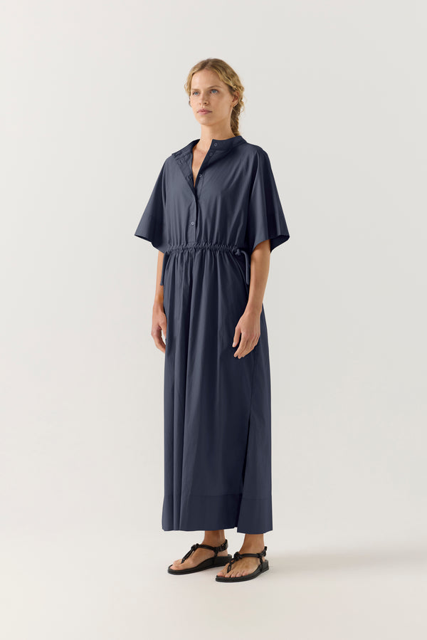 Woman wearing a dark blue dress with a white background