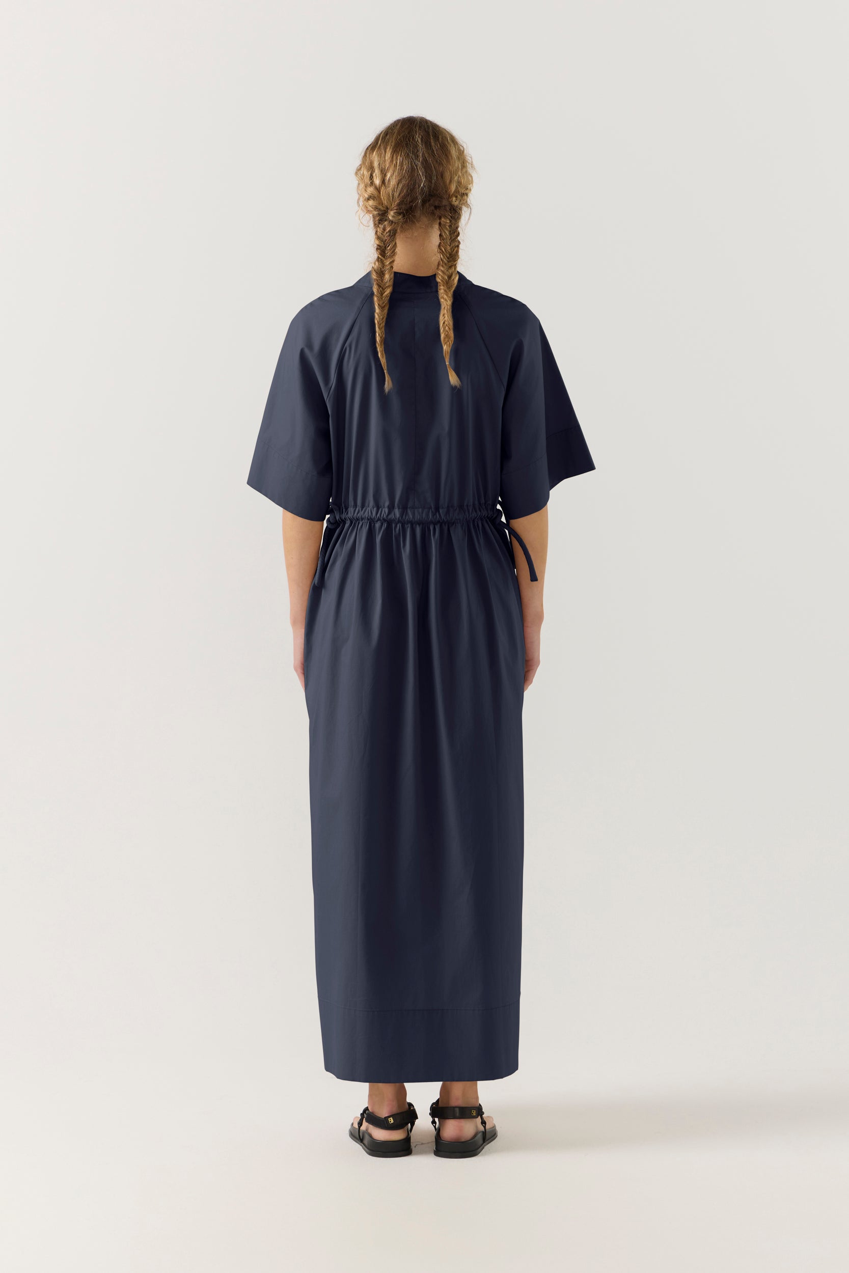 Woman wearing a dark blue dress with a white background