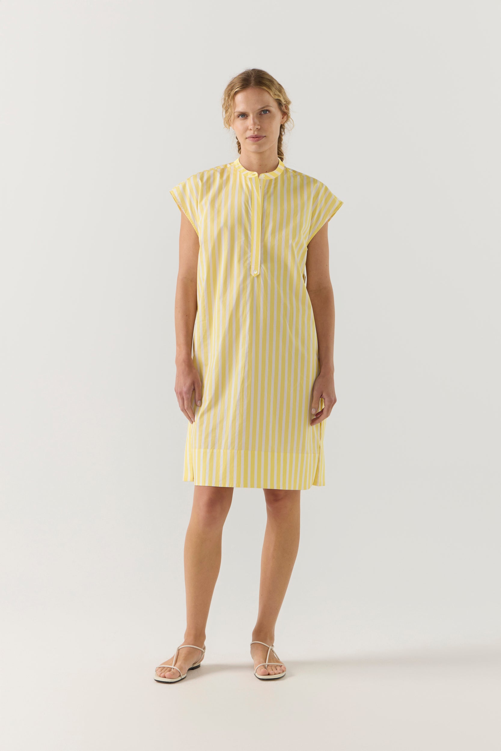 Woman wearing a yellow striped dress on a white background