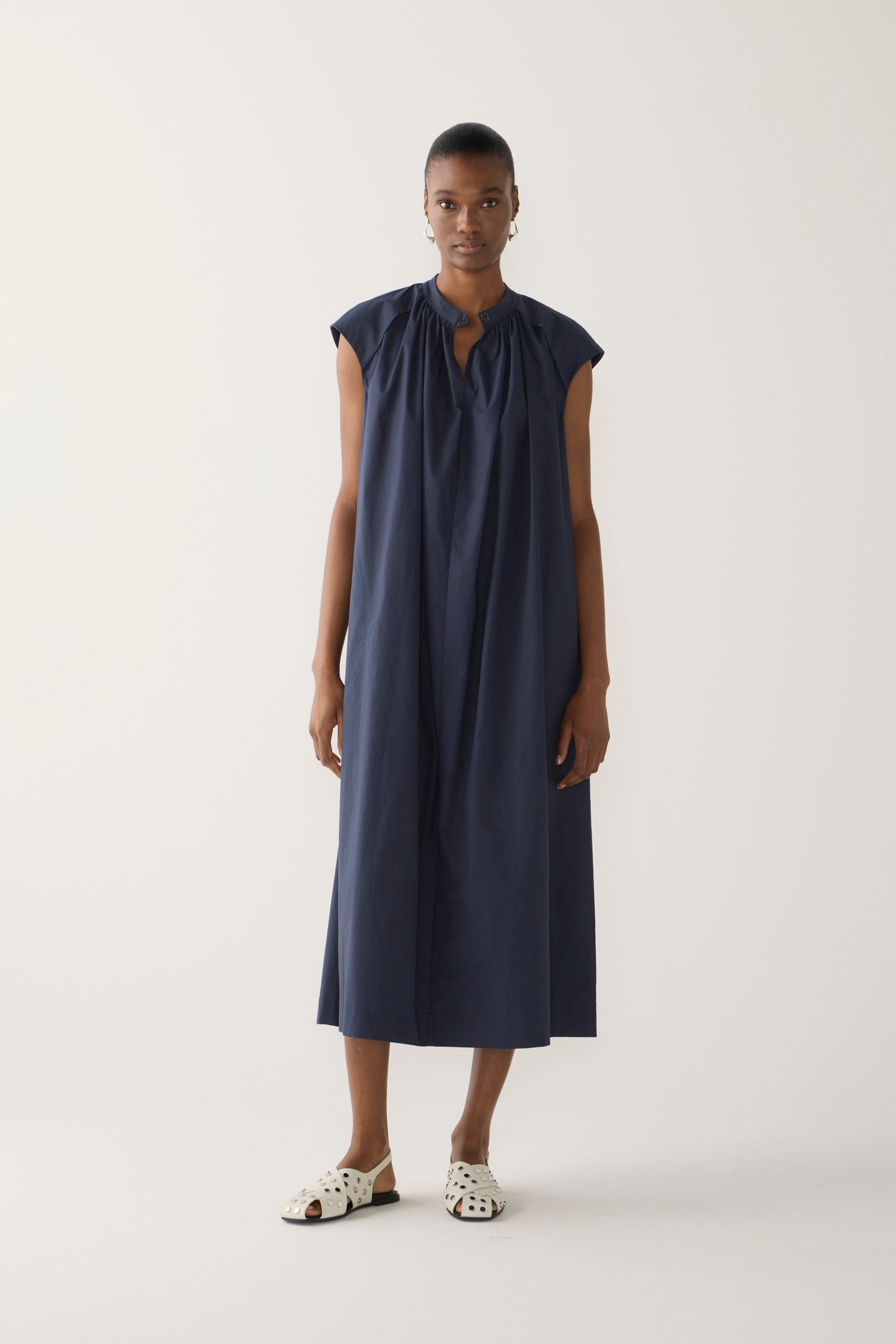 Woman wearing a navy sleeveless dress on a white background