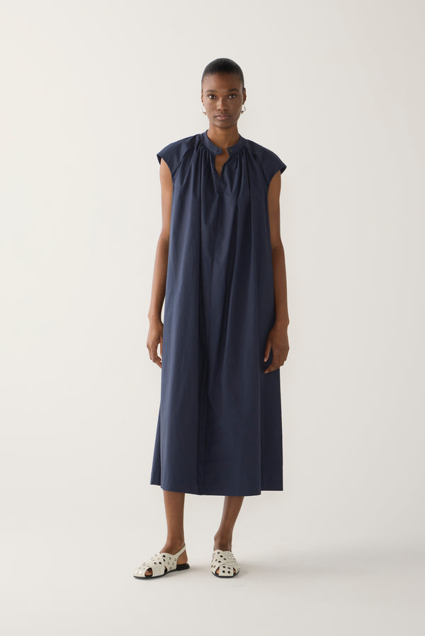 Woman wearing a navy sleeveless dress on a white background