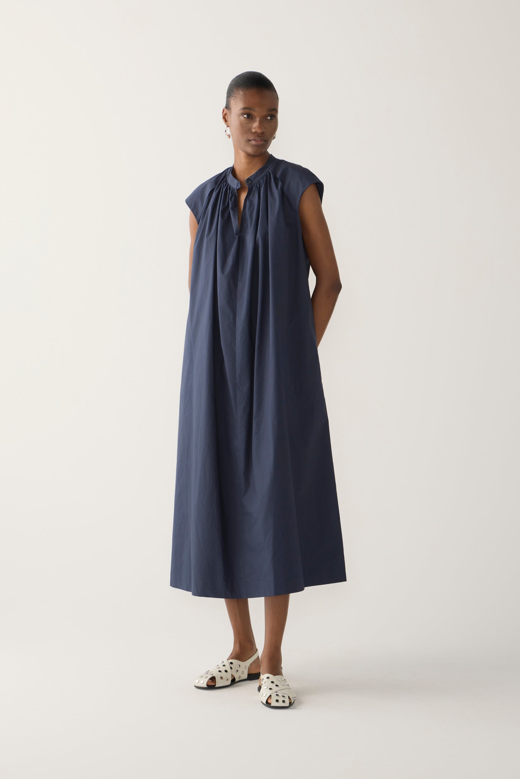 Woman wearing a navy sleeveless dress on a white background