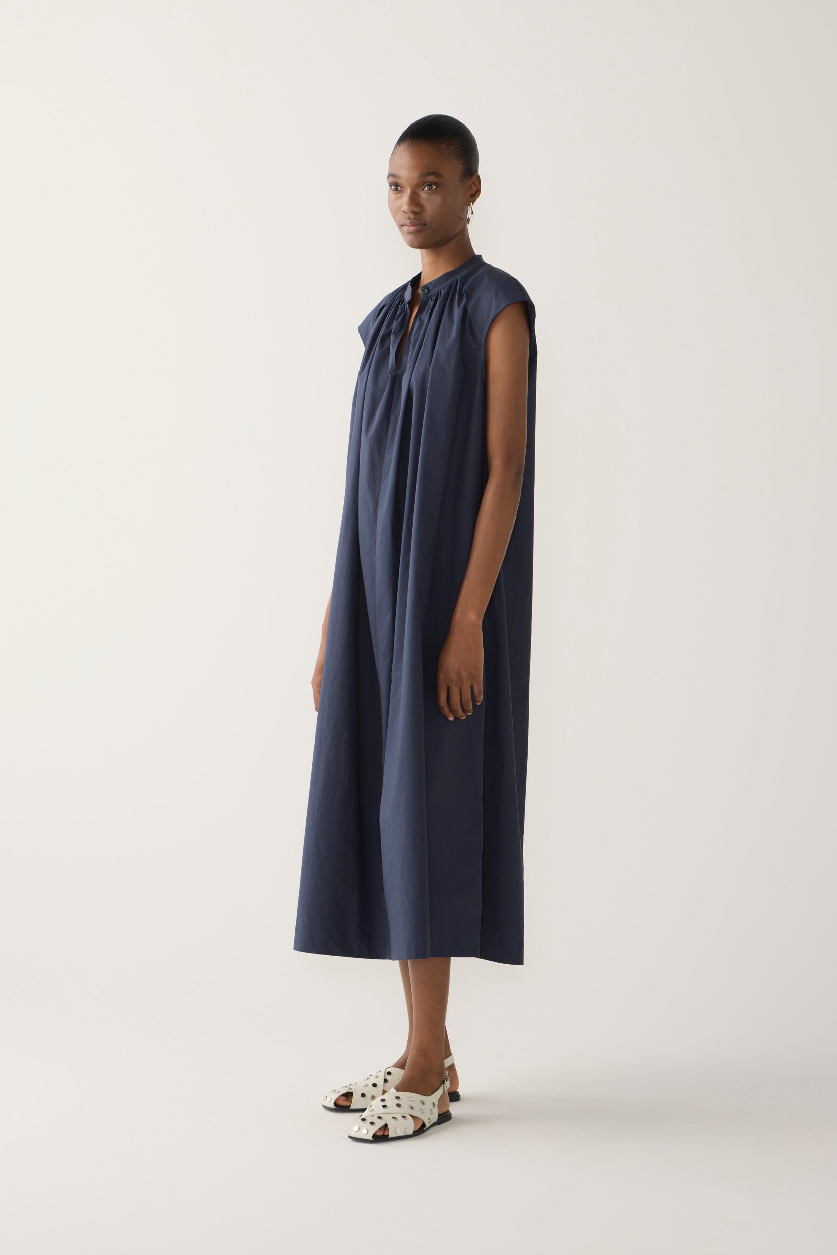 Woman wearing a navy sleeveless dress on a white background