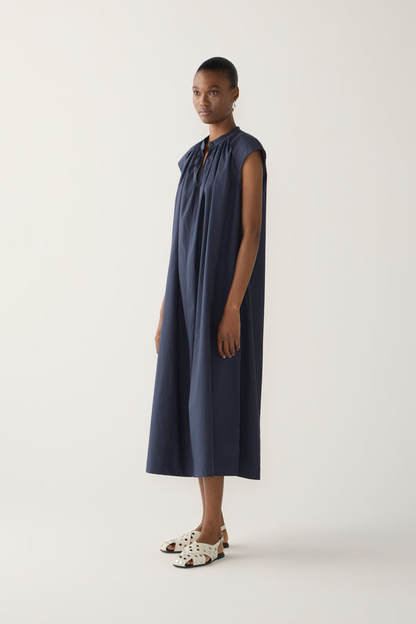 Woman wearing a navy sleeveless dress on a white background