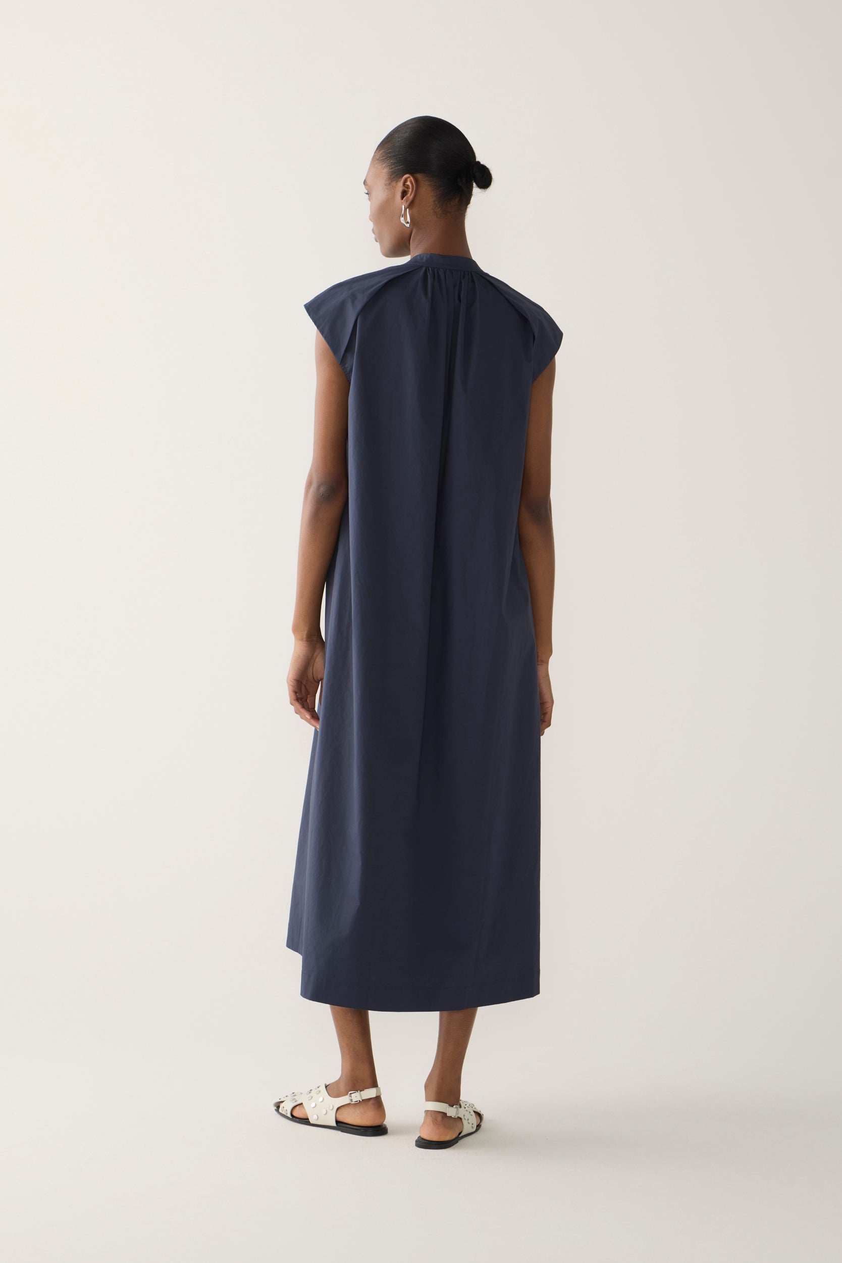 Woman wearing a navy sleeveless dress on a white background